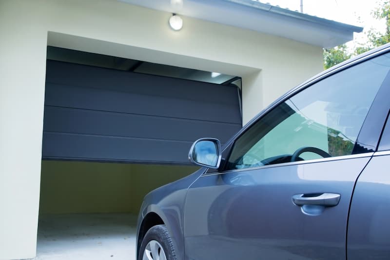 Silver car entering garage with dark gray garage door