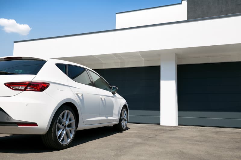 White car in front of two garage doors